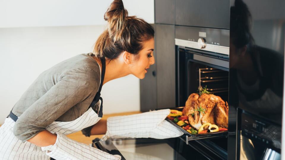 Young woman taking the dinner out of the oven