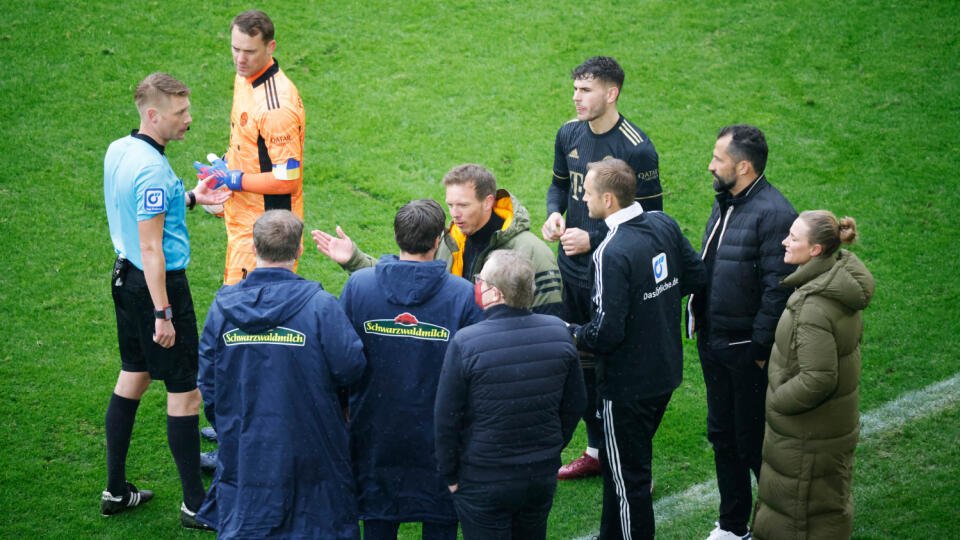 Rozhodca Christian Dingert (v modrom) preberá situáciu so štvrtým rozhodcom, s hráčmi a trénermi Bayernu Mníchov a SC Freiburg počas zápasu 28. kola nemeckej Bundesligy 2. apríla 2022 vo Freiburgu. Tréner Julian Nagelsmann z Bayernu Mníchov kritizoval vedenie Freiburgu, že sa odvolalo voči právoplatnosti výsledku víkendového zápasu nemeckej futbalovej Bundesligy. Bavori v ňom zdolali súpera 4:1, no na konci zápasu hrali chvíľu s dvanástimi hráčmi.