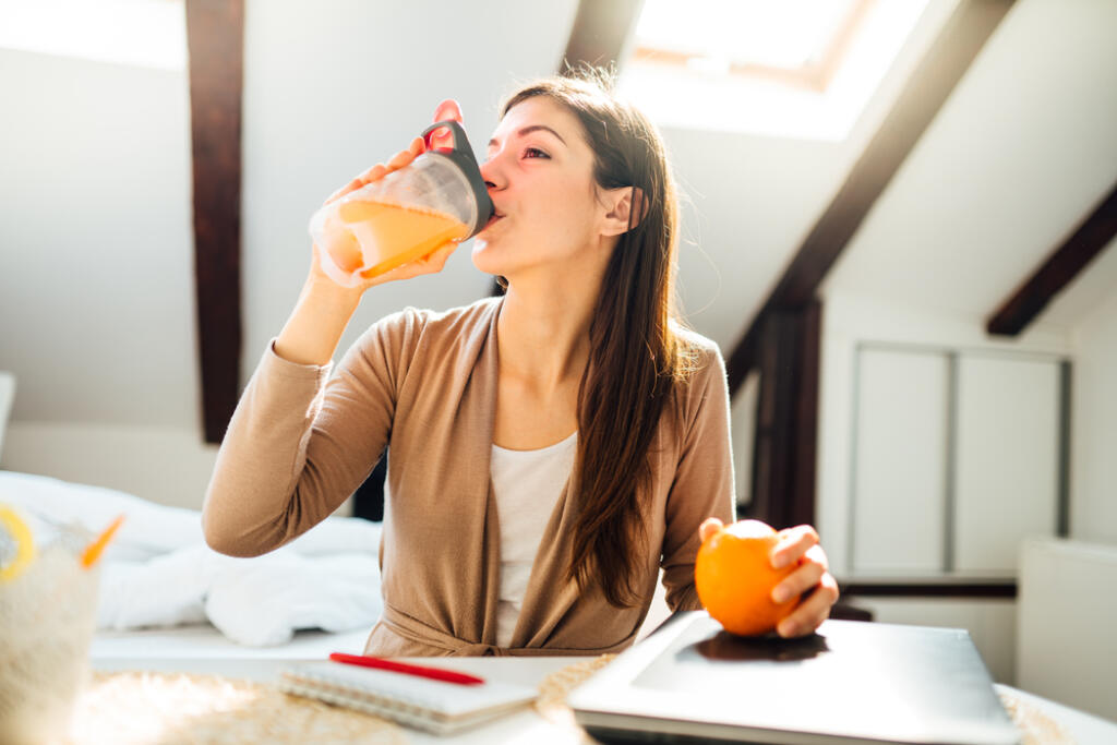 Woman,In,Home,Office,Drinking,Orange,Flavored,Amino,Acid,Vitamin