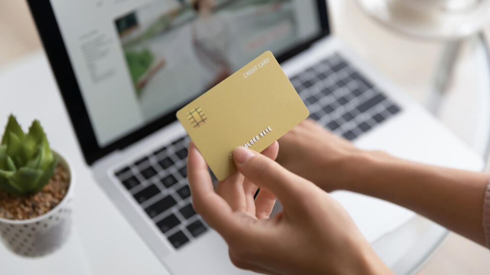 Close up woman holding golden plastic credit card mockup with number, paying online, girl using laptop, shopping online, doing internet secure payment, ordering and buying, ecommerce concept