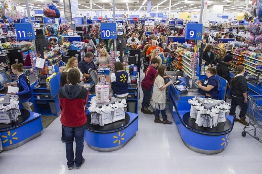 JB 16 Bentonville - Zákazníci stoja v rade na pokladne počas nakupovania v obchodnom dome Walmart v americkom Bentonville 27. novembra 2010 počas tradičných piatkových výpredajov na Deň Vďakyvzdania tzv. Black Friday. FOTO TASR/AP Liz Richardson, left, and her daughter Aubrey, 2, fill their cart with a 32