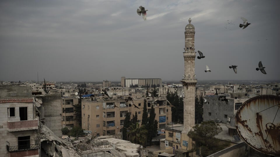 Mešita stojí pri zničenej budove v sýrskom meste Idlib 18. marca 2020, ktoré je poslednou baštou povstaleckých bojovníkov a džihádistov bojujúcich proti vláde sýrskeho prezidenta Bašára Asada.