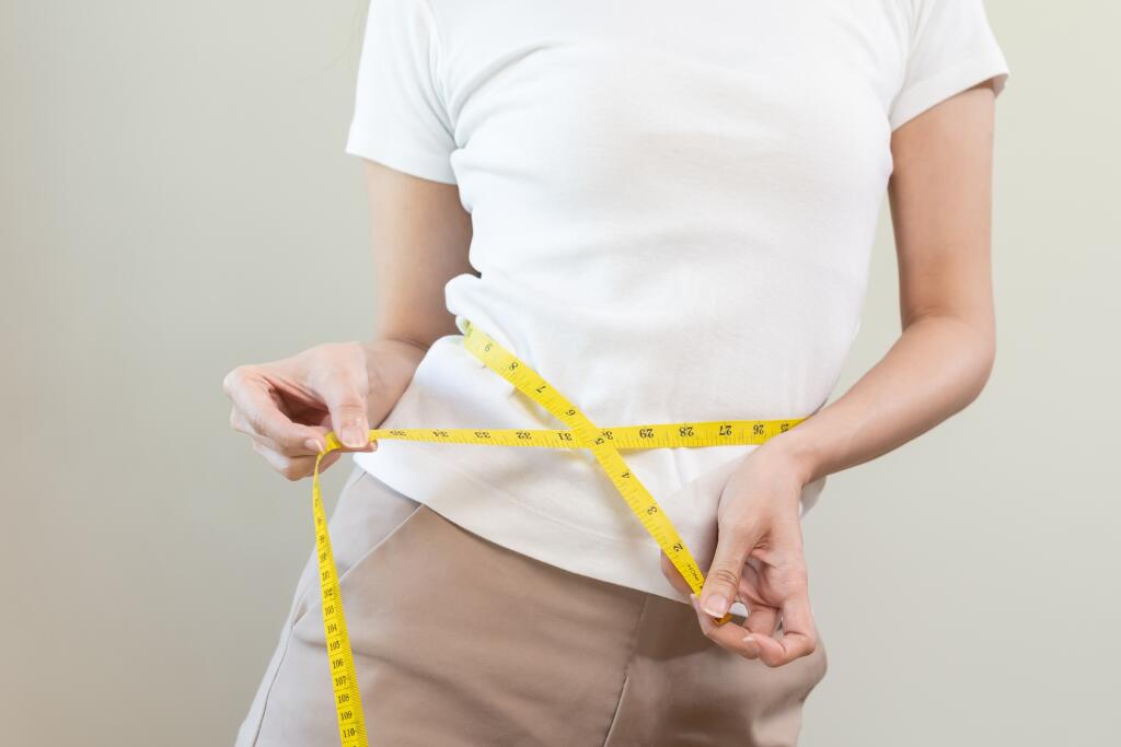 Diet, slim shape asian young woman standing, hand using measure tape around waist, body. Happy, pleasure girl slim slender on white background. Diet session for wellbeing health, eat good food people.