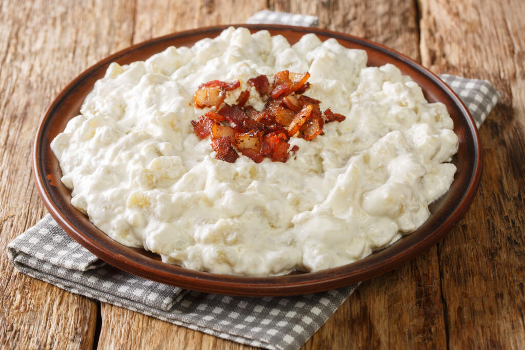 Slovak national dish Bryndzove halusky is made of small potato dumplings and a creamy cheese sauce closeup in the plate on the table. horizontal