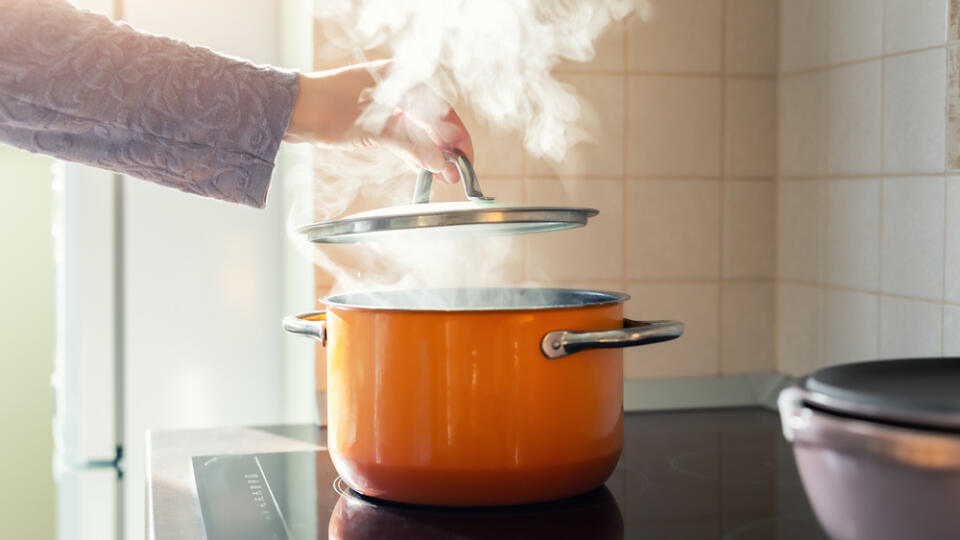 Female,Hand,Open,Lid,Of,Enamel,Steel,Cooking,Pan,On