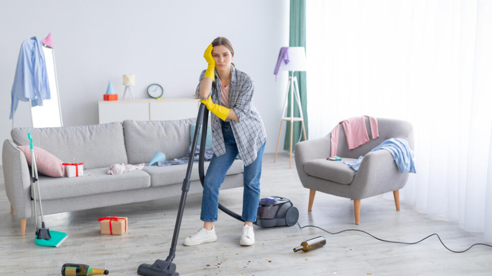 Unhappy,Young,Woman,Standing,With,Vacuum,Cleaner,In,Messy,Flat