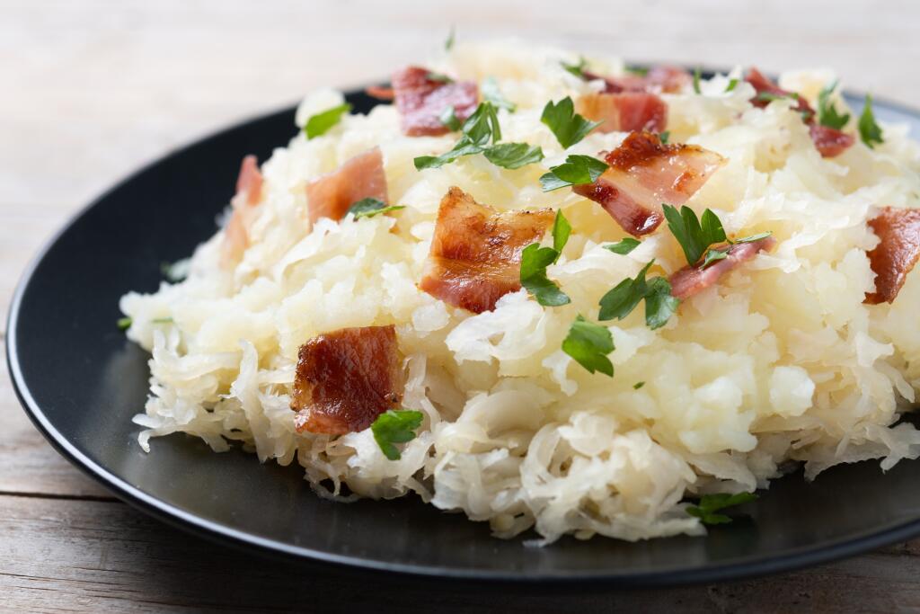 Slovak potato dumplings halusky with steamed sauerkraut and bacon on wooden table