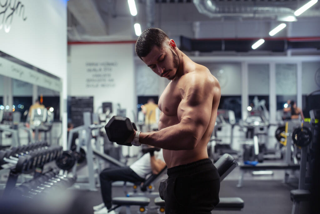 Young,Bodybuilder,Working,Out,With,Dumbbells,Weights,At,The,Gym