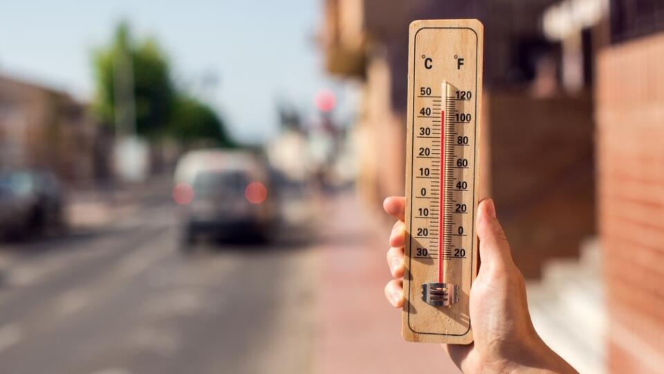 Hot,Weather.,Thermometer,In,Hand,In,Front,Of,An,Urban