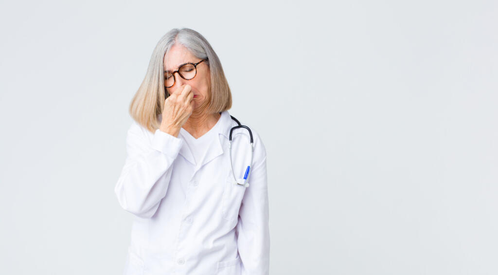 Middle,Age,Doctor,Woman,Feeling,Disgusted,,Holding,Nose,To,Avoid