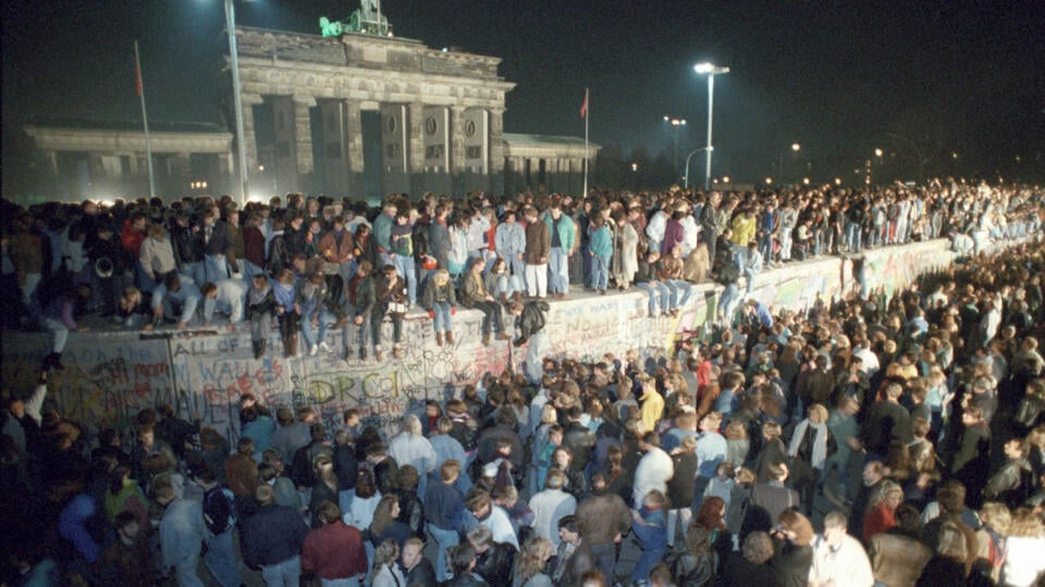 Na archívnej snímke ľudia stoja na Berlínskom múre pred Brandenburskou bránou v centre Berlína z 9. na 10. novembra 1989. V nemeckej metropole sa v pondelok 4. novembra 2019 začínajú týždňové spomienkové oslavy pádu Berlínskeho múru, ku ktorému došlo pred 30 rokmi.