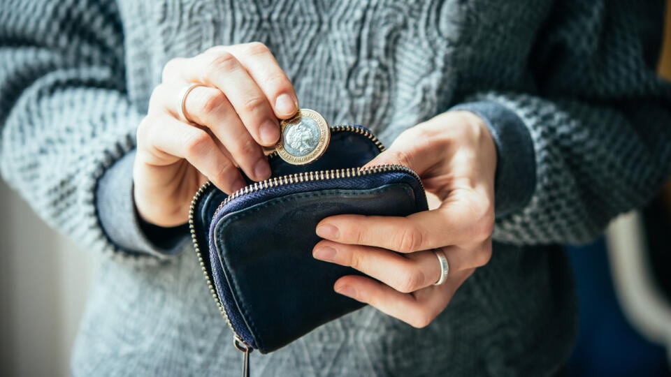 Hands,Holding,British,Pound,Coin,And,Small,Money,Pouch