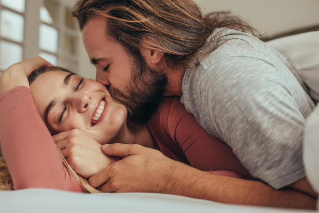 Couple,In,Bed,Spending,Time,Together,With,Man,Kissing,His