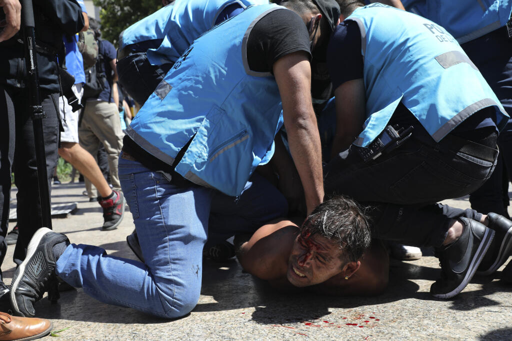 Kk5 Buenos Aires - Policajti zatýkajú fanúšika počas rozlúčky s argentínskym futbalistom Diegom Maradonom pred prezidentským palácom 26. novembra 2020 v Buenos Aires. Telo futbalistu Diega Maradonu vo štvrtok vystavili v sídle argentínskej federálnej vlády. O osobnú rozlúčku prejavili záujem davy ľudí. Neskôr sa však situácia vyhrotila, fanúšikovia sa v snahe dostať dnu hádzali na policajtov fľašky či kusy oplotenia. Bezpečnostné zložky v jednom prípade použili slzotvorný plyn. FOTO TASR/AP
Pol