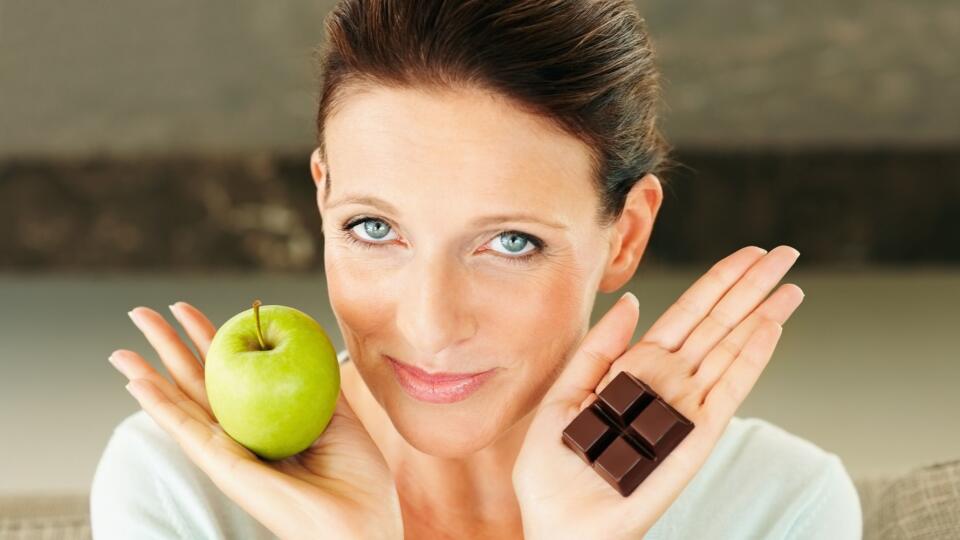 Woman holding an apple and a piece of chocolate