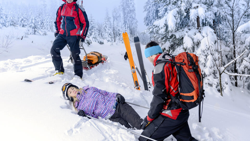 Rescue ski patrol help injured woman skier lying in snow