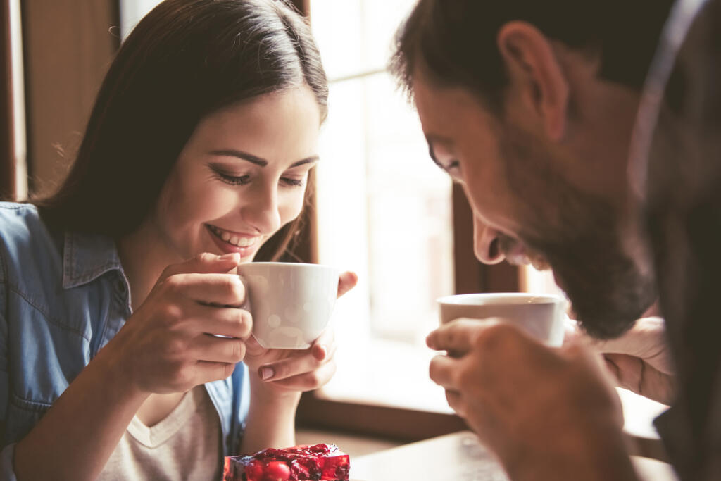 Happy,Young,Couple,Is,Drinking,Coffee,And,Smiling,While,Sitting