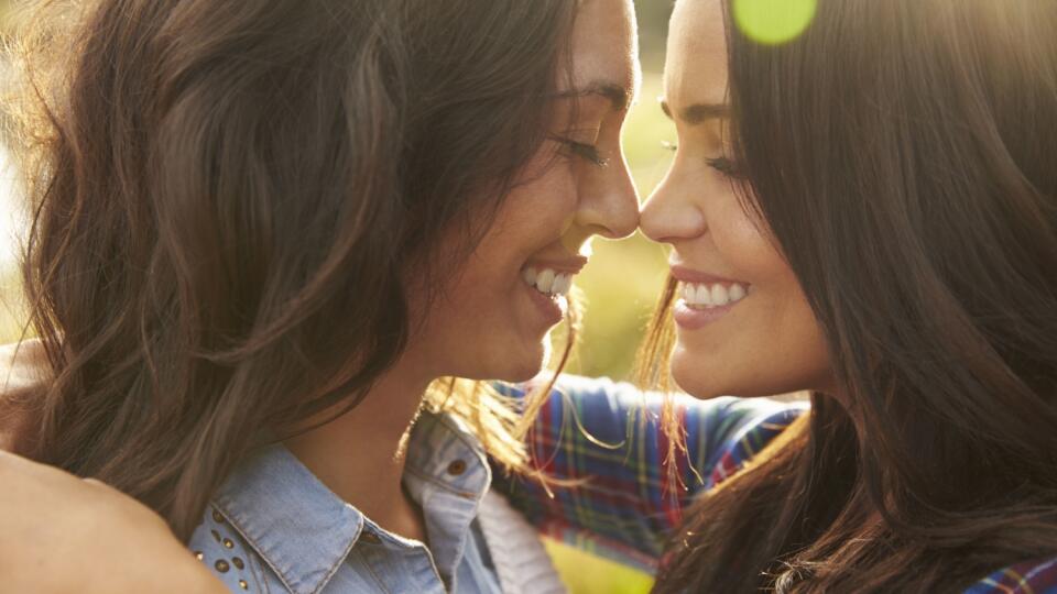 Lesbian couple embrace touching noses, eyes closed, close up