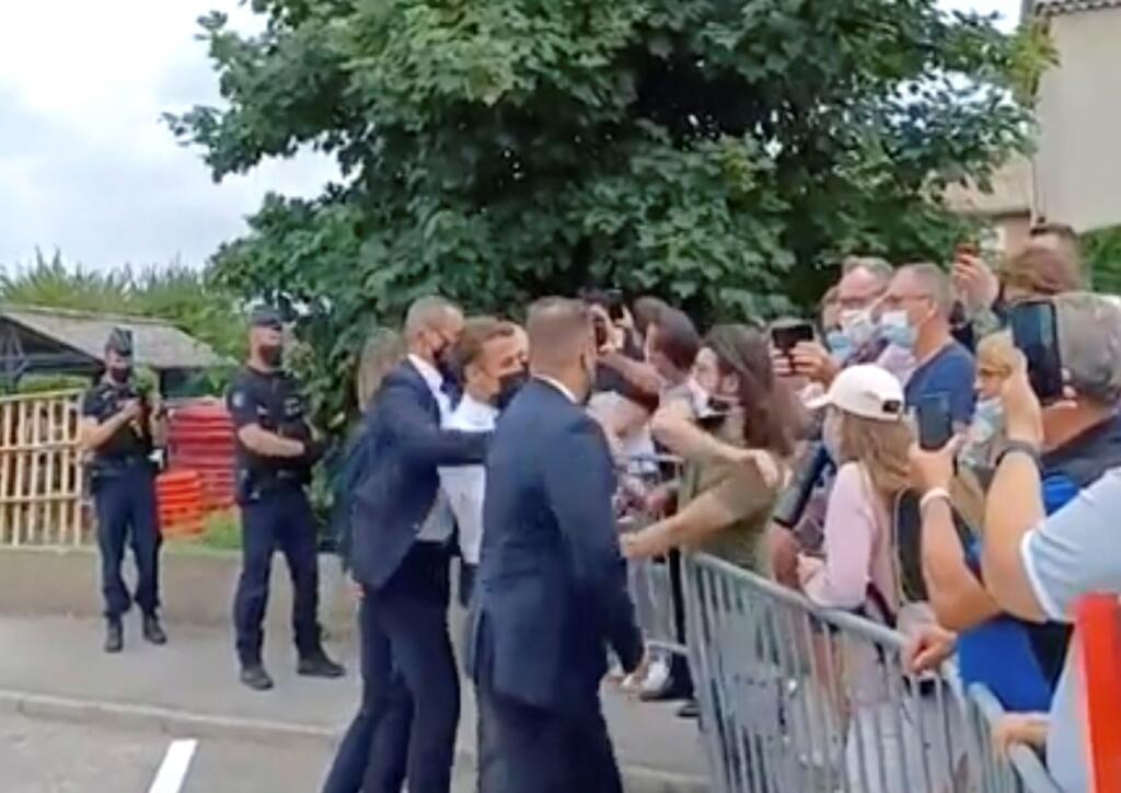 Na videosnímke francúzsky prezident Emmanuel Macron (uprostred) dostáva facku od muža (v zelenom tričku) počas Macronovej návštevy  v obci Tain-l'Hermitage v departemente Drôme v regióne Rhône-Alpes na juhovýchode Francúzska 8. júna 2021.   FOTO TASR/AP