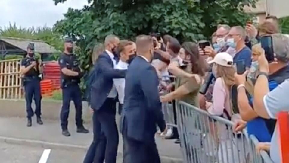 Na videosnímke francúzsky prezident Emmanuel Macron (uprostred) dostáva facku od muža (v zelenom tričku) počas Macronovej návštevy v obci Tain-l'Hermitage v departemente Drôme v regióne Rhône-Alpes na juhovýchode Francúzska 8. júna 2021. FOTO TASR/AP