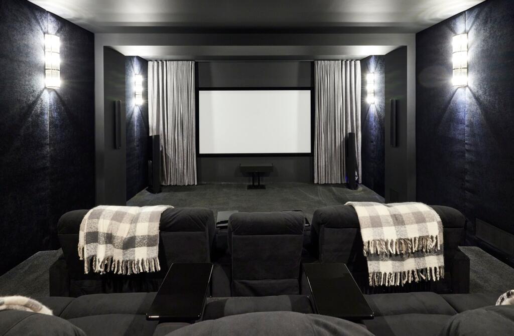Podzemie však ukrýva aj kinosálu, ktorá je vybavená vlastným zvukovým panelom od Edmonton's Eldrick Upholstery + Interiors, dotvára čierny automat na popcorn.