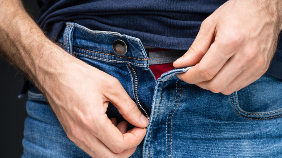 Midsection,Of,A,Man's,Hand,Unzipping,His,Blue,Denim,Jeans