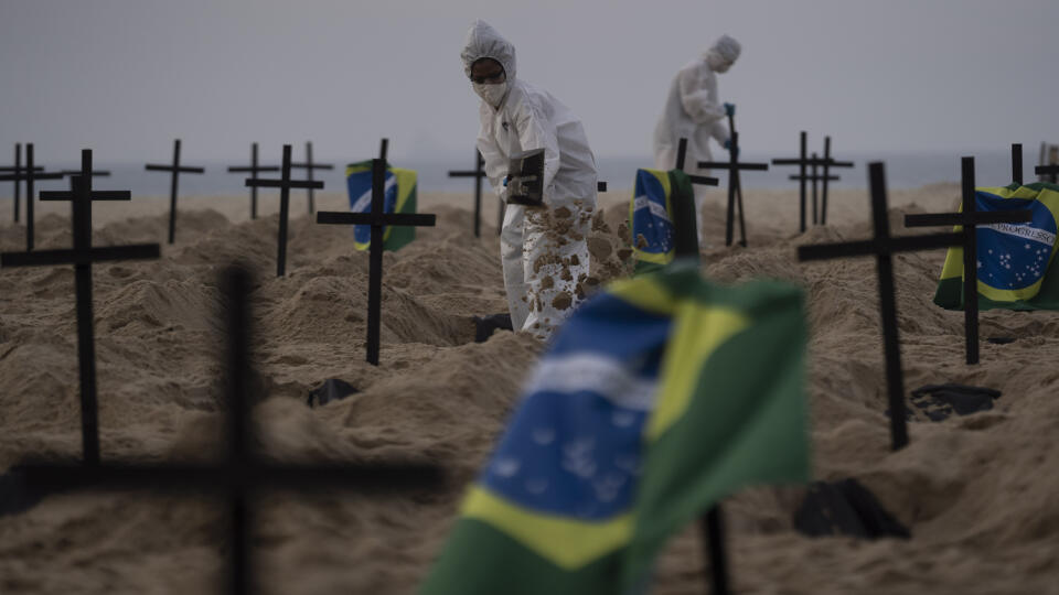 Aktivisti v špeciálnych ochranných odevoch vykopávajú hroby na slávnej pláži Copababana v brazílskom meste Rio de Janeiro vo štvrtok 11. júna 2020.