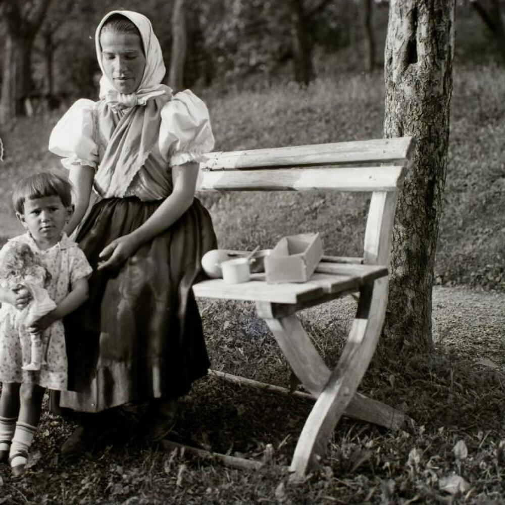 K slovenským tradíciám neodmysliteľne patria aj kroje. Na tejto fotografii z Banskej Bystrice z roku 1932 je žena v kroji s dcérou. Je to príklad klasického dobového oblečenia.