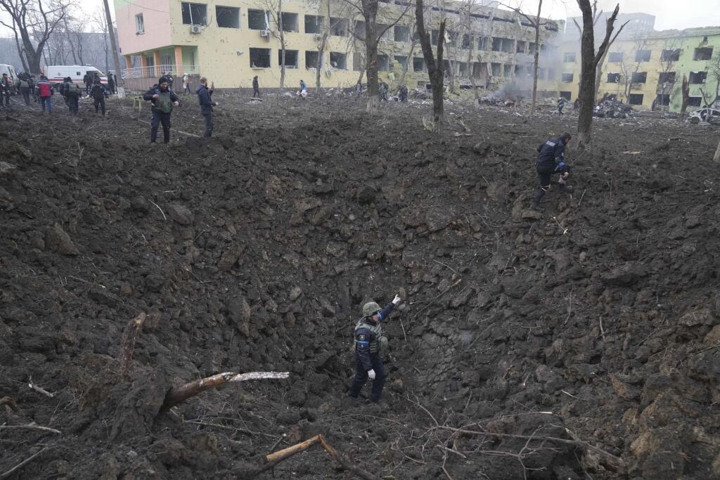 KK41 Mariupol - Na snímke ukrajinskí vojaci a dobrovoľníci pracujú na mieste zničenej budovy pôrodnice po ostreľovaní v Mariupole počas štrnásteho dňa ruskej invázie na Ukrajine v stredu 9. marca 2022. Ruská armáda pri stredajšom ostreľovaní ukrajinského mesta Mariupol zasiahla a zničila detskú nemocnicu a pôrodnicu, tvrdia miestni činitelia aj ukrajinský prezident Volodymyr Zelenskyj. TASR túto informáciu prevzala zo stanice Sky News. FOTO TASR/AP  

Ukrainian soldiers and emergency employees w